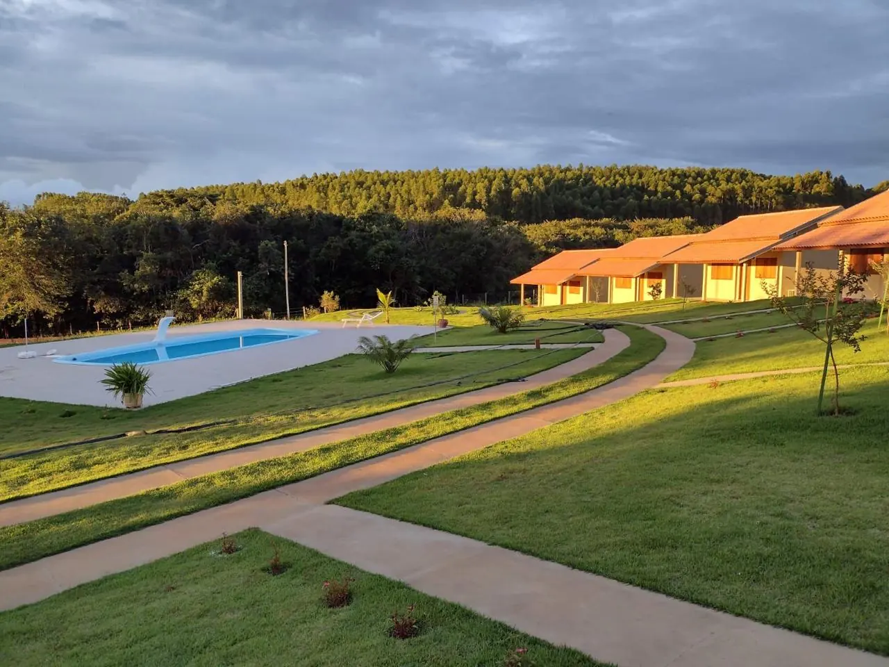 Pousada com gramado de esmeralda entre caminhos de cimento, ao entardecer